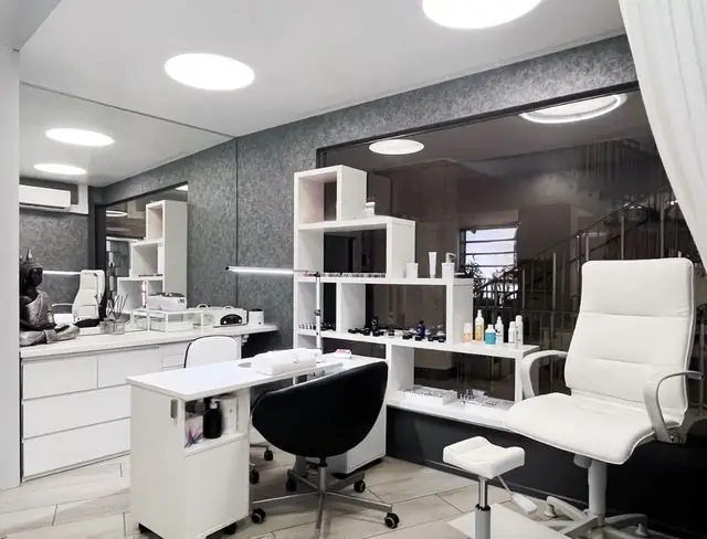 Espace onglerie lumineux, fauteuils blancs et étagères de produits