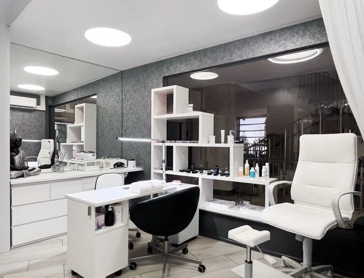 Espace onglerie lumineux, fauteuils blancs et étagères de produits